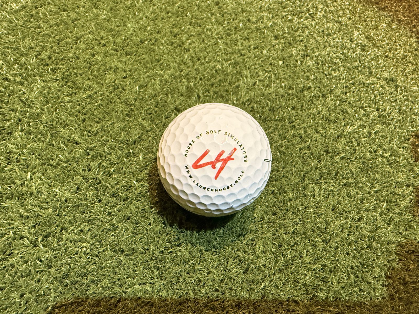 A Launch House branded golf ball on the hitting mat
