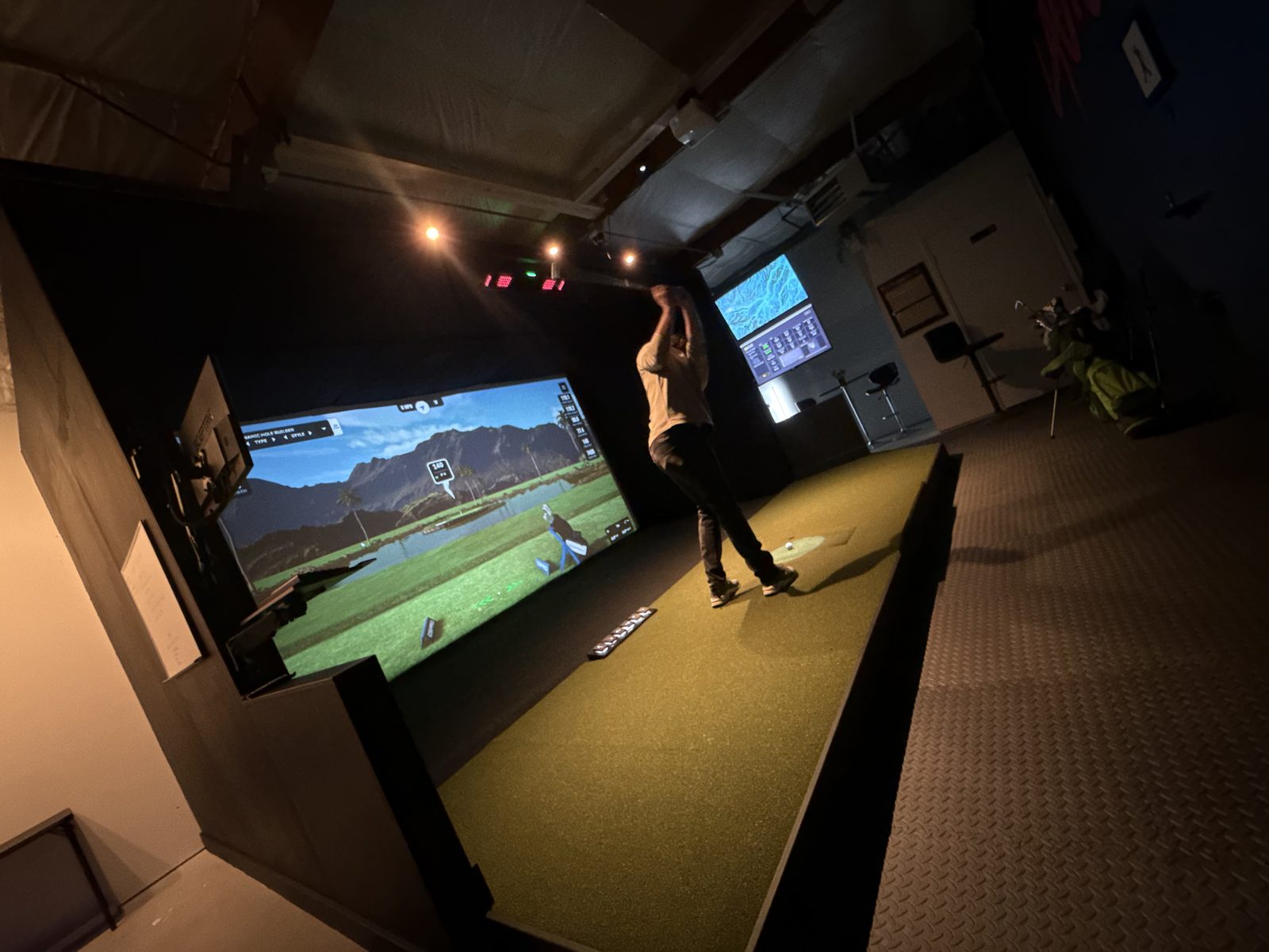 Wide view of the Launch House Hillsboro simulator bay with a golfer swinging